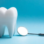 A white tooth next to a special dental mirror used at the dentist in cedar park against a blue background