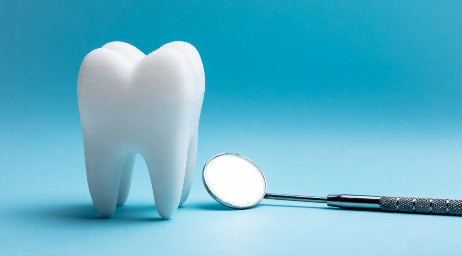 A white tooth next to a special dental mirror used at the dentist in cedar park against a blue background