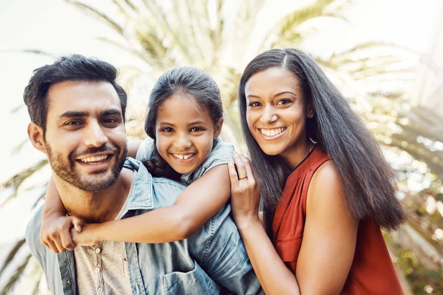 Dad, young daughter and Mom smiling with beautiful teeth.