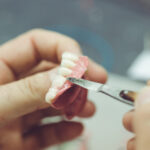 Closeup of a technician creating a custom made denture.