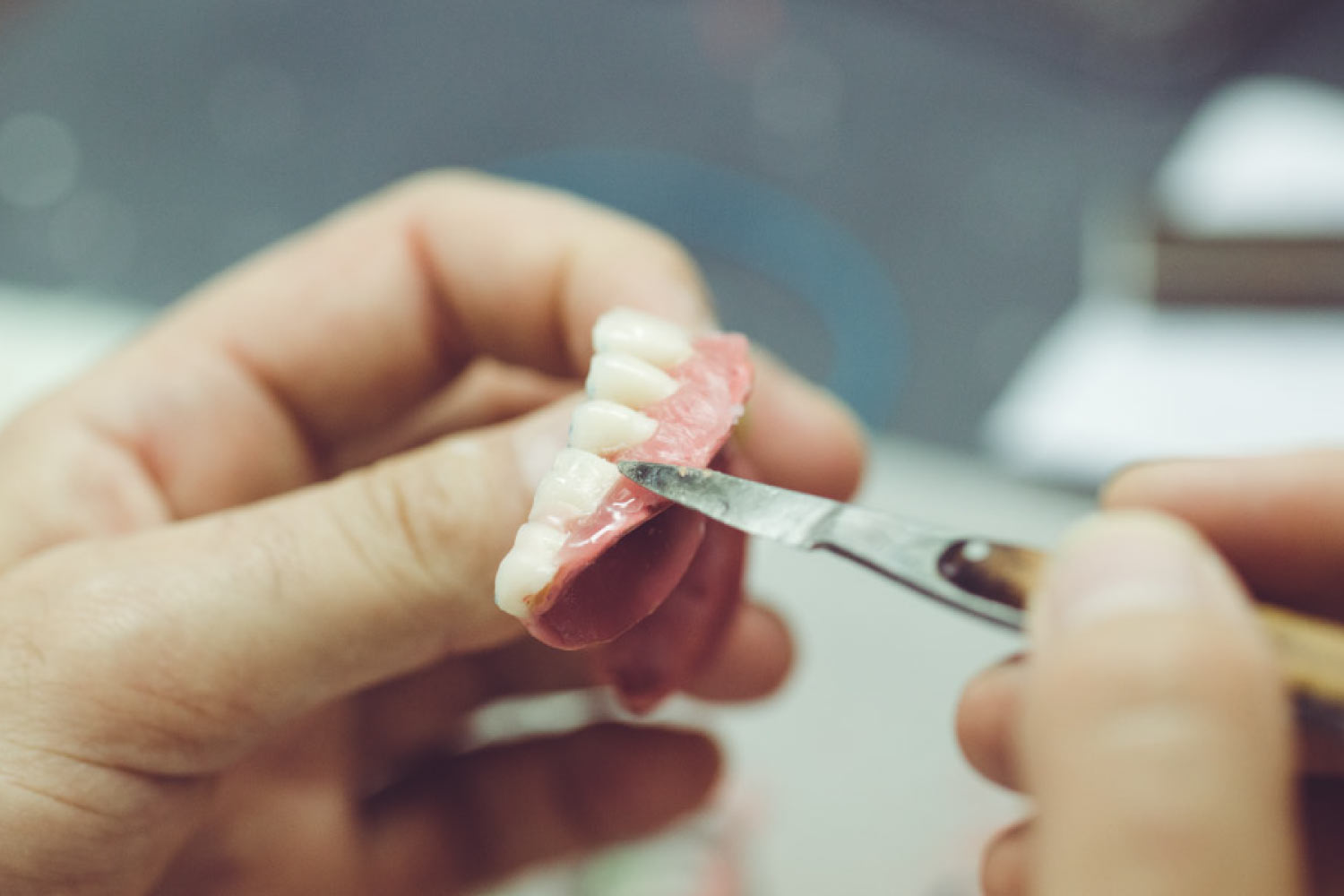 Closeup of a technician creating a custom made denture.