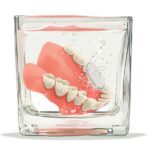 Dentures sitting in a glass getting cleaned.
