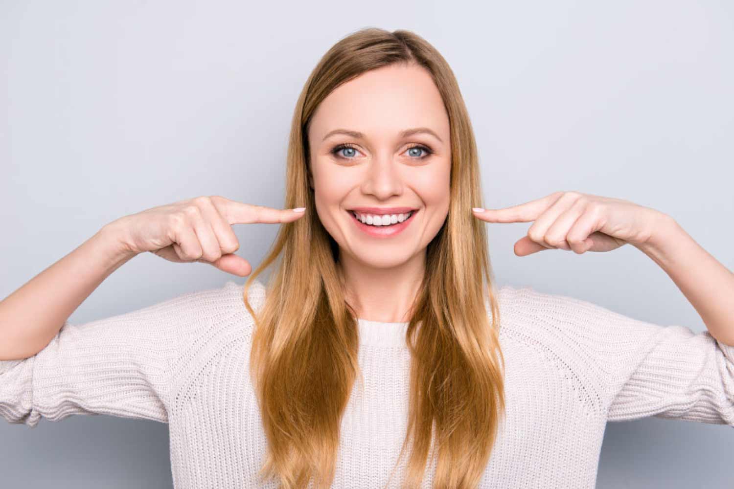 Smiling woman points to her while teeth.