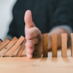 preventive dentistry helps make dentistry more affordable by stopping things in their tracks like these wooden dominoes being blocked by a hand