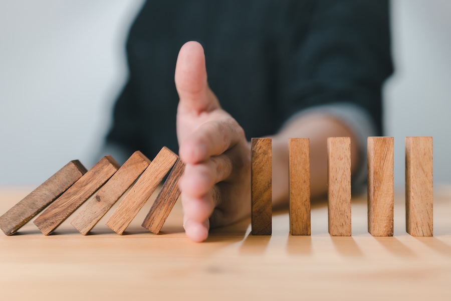 preventive dentistry helps make dentistry more affordable by stopping things in their tracks like these wooden dominoes being blocked by a hand